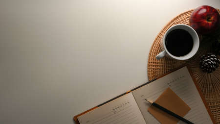 Comfortable and cozy workspace with diary book, coffee mug, decor and copy space on white table. Reading, writing table.の写真素材