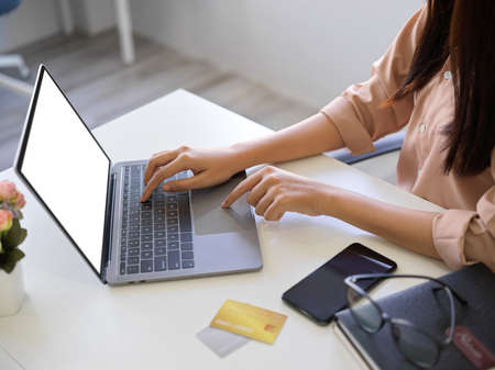 Close-up image of an Asian businesswoman typing on laptop keyboard, researching some informations on the internet.の写真素材