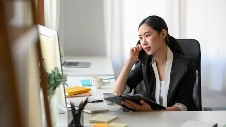 An Asian female entrepreneur is talking with her supplier on the phone. A businesswoman is calling her partner.の写真素材