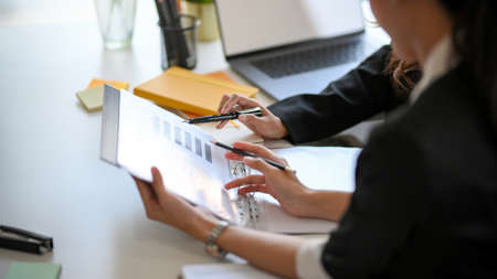 Cropped shot of a financial consultant team analyse the data on a report with their manager.の写真素材