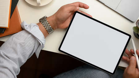A man uses a stylus pen to draw on a tablet screen. Tablet touchpad blank screen mockup. top viewの写真素材