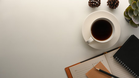 Comfortable office desk or worktable with coffee cup, diary book, decor and copy space on white background.の写真素材