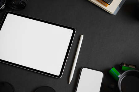 Modern dark office desk with a mockup screen of tablet computer on black background. top viewの写真素材
