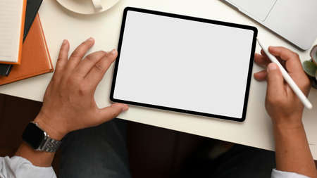 Successful businessman using portable tablet computer at his workspace. top viewの写真素材