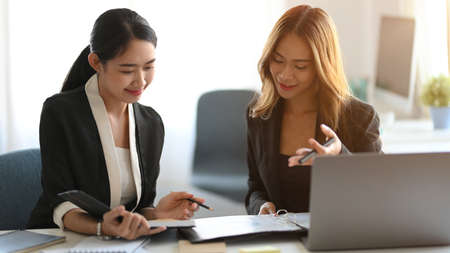 Two businesswoman working together in the office. Executive manager and her business partner having a private meeting to summarise the project.の写真素材