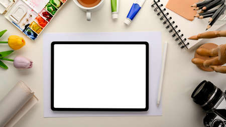 Artist workspace with painting tools, work tools and tablet computer blank screen mockup for your graphic image presentation. Top viewの写真素材