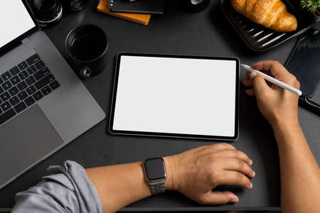 Professional businessman using digital tablet computer at his modern office desk. Tablet touchpad...