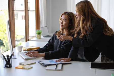 A professional marketing manager helping her assistant to recheck the project strategy plan on desktop computer.の写真素材