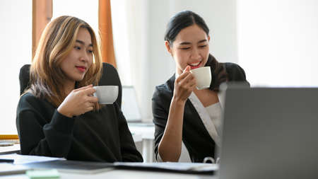 Two Asian female managers are having a hot coffee during a meeting and discussing business plans in the office.Â の写真素材