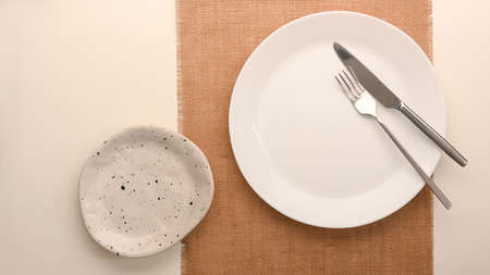 Simple minimal white plate with silverware over placemat on dining table. top viewの写真素材