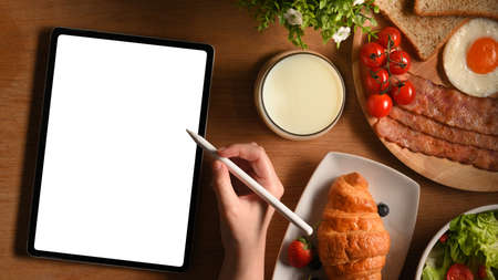 Top view, A female sketching on digital tablet with a breakfast set on table. Template for your recipe or menu.の写真素材
