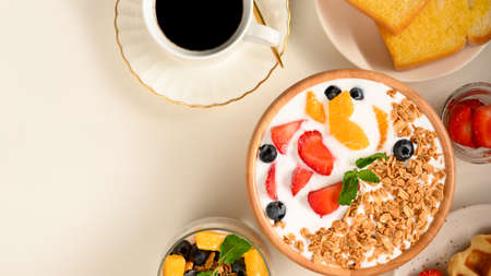 Dietary breakfast concept, Healthy yoghurt bowl with fresh fruits, black coffee and toasts. top viewの写真素材
