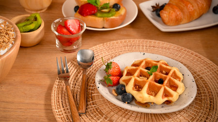Dessert concept, Waffle with honey syrup and fresh berries on a wooden table. close-up imageの写真素材