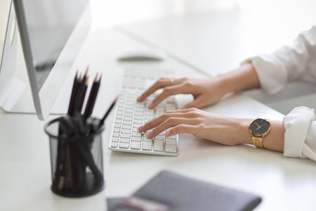 Side view, A businesswoman working in the modern office, typing on computer keyboard at her desk.の写真素材