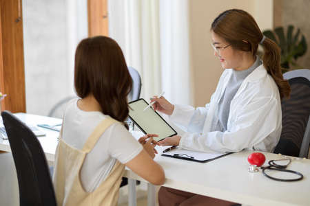 Asian young female doctor explain the medical treatment to female patient in the hospital office.の写真素材