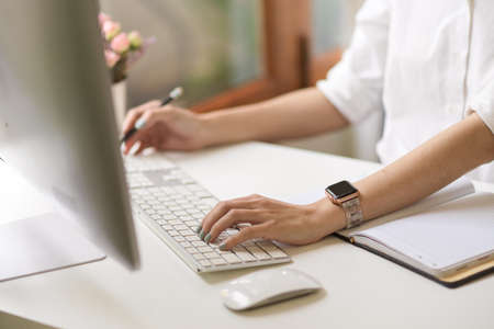 A businesswoman or female working on desktop computer, browsing the internet, researching some...