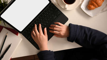 Top shot of a female freelancer working on a tablet computer, searching an online job on the website at her home workspace.の写真素材