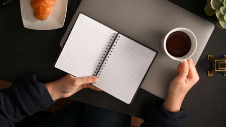 A businesswoman reading a book while sipping coffee in the morning at her office desk. top viewの写真素材