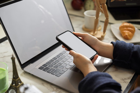 A female using her smartphone on office worktable. A woman messaging to her colleagues.