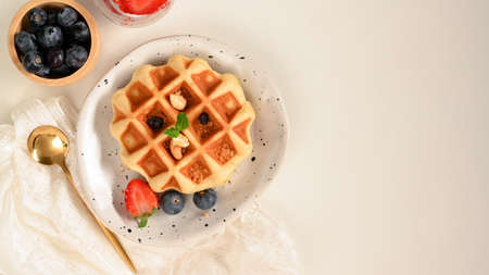 Waffle with fresh berries and maple syrup on white table with copy space for your presentation.の写真素材