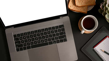 Simple office workspace with laptop computer blank screen mockup, easy breakfast set and stationery on table. top viewの写真素材