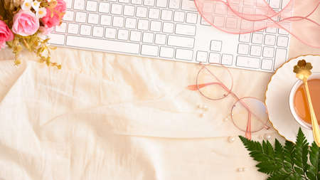 Modern beautiful stylish feminine workspace concept with computer keyboard, eye-glasses, tea cup, flowers and copy space. top view, flat layの写真素材