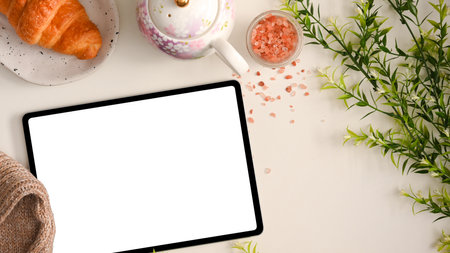 Feminine workspace concept, Digital tablet computer with white screen display on beautiful workspace with afternoon tea set.の写真素材