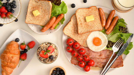 Tasty homemade breakfast set on white dining table. Flat lay, hotel breakfast set concept. Croissant, ham, bacon, sausages, egg and salad.の写真素材
