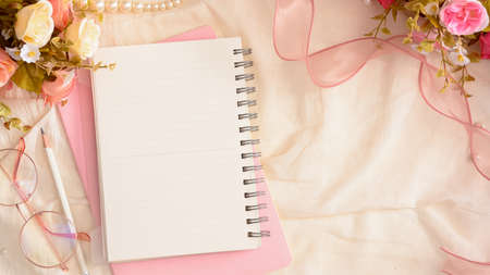 Empty notepad paper with copy space and beautiful feminine decorations on white table. flat layの写真素材