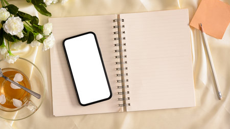 Female workspace, Feminine office desk, A smartphone blank screen mockup on notebook and decor on tableの写真素材