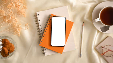 Cozy and comfort women's workspace with smartphone blank screen mockup and accessories on table. top view, flat layの写真素材
