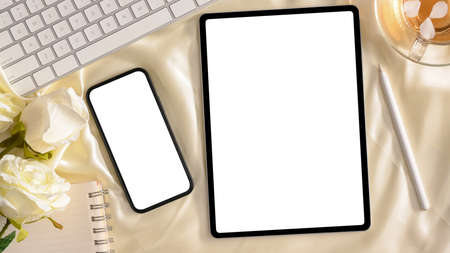 Top view, Female's workspace with smartphone blank screen, tablet computer white screen mockup.の写真素材
