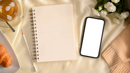 Feminine workspace, Minimal white worktable with smartphone blank screen mockup, empty notebook and decors. top viewの写真素材