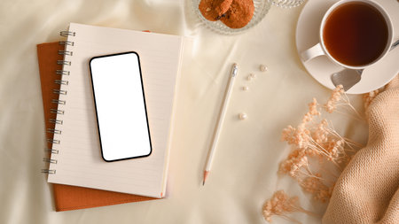 Comfort feminine workspace with smartphone white screen mockup over books on white table. top viewの写真素材