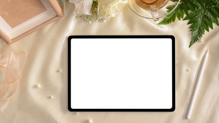 Feminine workspace for online work concept, Digital tablet touchpad mockup on white silk background with feminine decor. top viewの写真素材