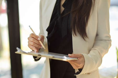 Cropped shot, Businesswoman standing in the office and holding a financial clipboard paperwork.の写真素材