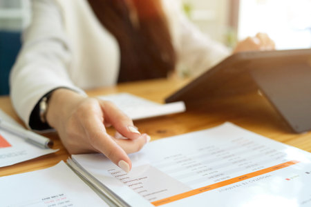 Selective focus, closeup image of a businesswoman pointing her finger on financial report paperwork.の写真素材