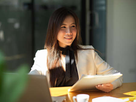 Beautiful female manager sitting in her office room and working on her project report. Asian businesswoman conceptの写真素材