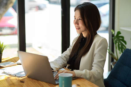 Beautiful Asian office lady or businesswoman working on her portable laptop in the coffee shop.