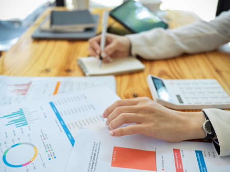 Close-up shot of a female accountant or financial analysts examining financial report in the office.の写真素材