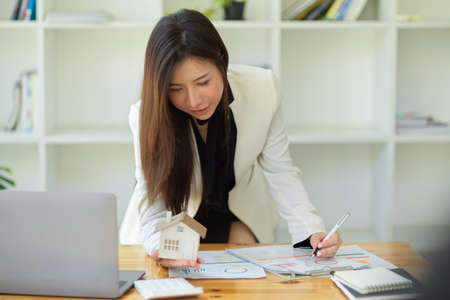 Gorgeous asian female investment broker or real estate agent leaning on table and working, planning...