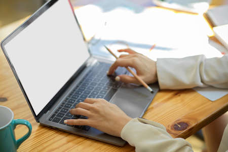 Close-up, a businesswoman or college student typing on keyboard, using laptop computer on tableの写真素材