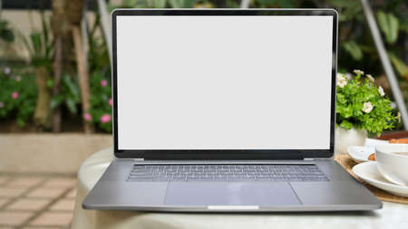 Portable laptop computer white screen mockup on a table in outdoor cafe coffee shop. close-up imageの写真素材