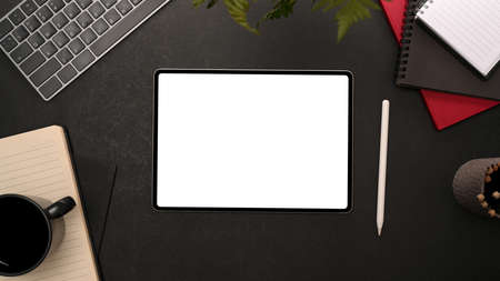 Black office desk top view with a digital tablet computer white display mockup and office supplies....
