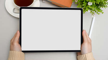 Top view, Female hands holding a digital tablet computer over modern workspace. tablet blank screen.