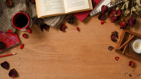 Vintage feminine workspace background with novel books, coffee cup, roses bouquet, and decor on wooden table background. top viewの写真素材