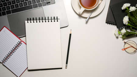 Students worktable space with stationery and electronic device on white table. Blank spiral notepad for your text. top viewの写真素材