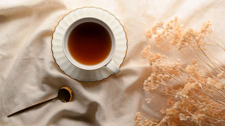Afternoon tea concept, A tea cup with dried flowers on minimal white tablecloth. top viewの写真素材