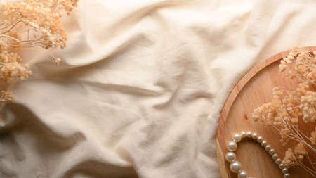 Minimal vintage feminine background with dried flowers, pearl necklace on wooden tray, copy space on minimal tablecloth. top viewの写真素材