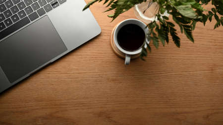 A modern office table with notebook laptop computer, decor plant, coffee cup and copy space on...